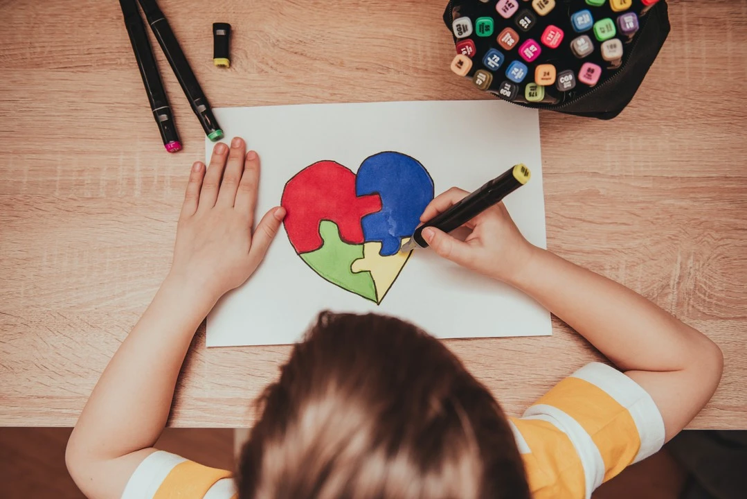 dziecko koloruje namalowane na kartce serce